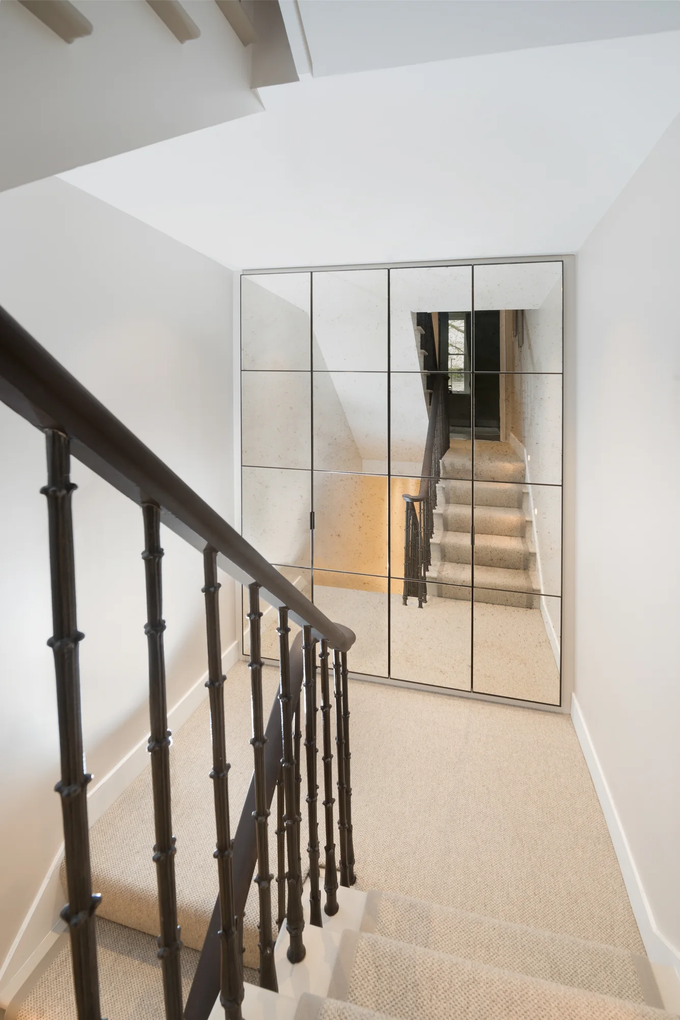 Closed antique-effect mirrored wardrobe doors beside the staircase