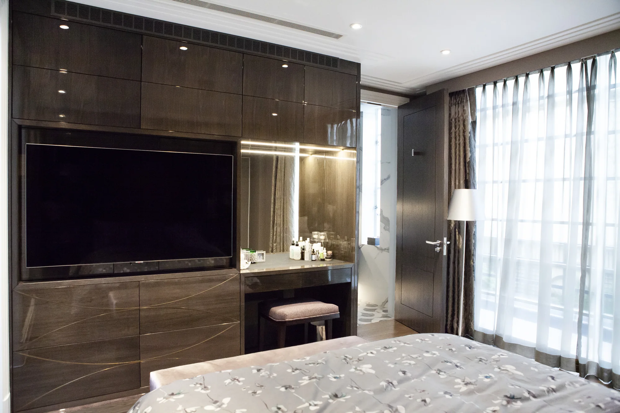 Overall bedroom TV wall with glossy cupboards and an illuminated dressing table
