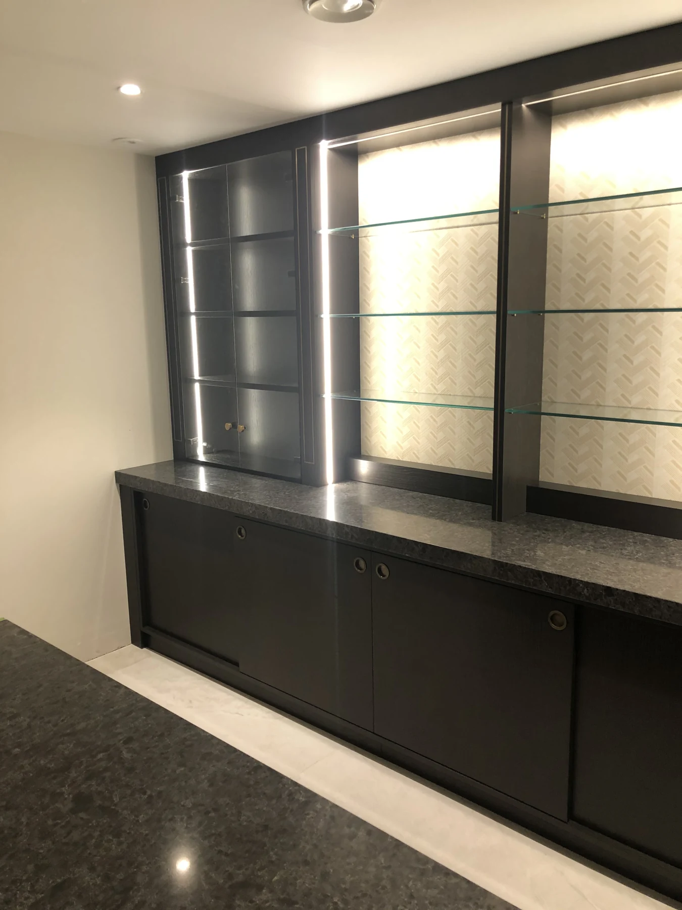 Side view of the black back-bar cupboards, display shelves and lighting.