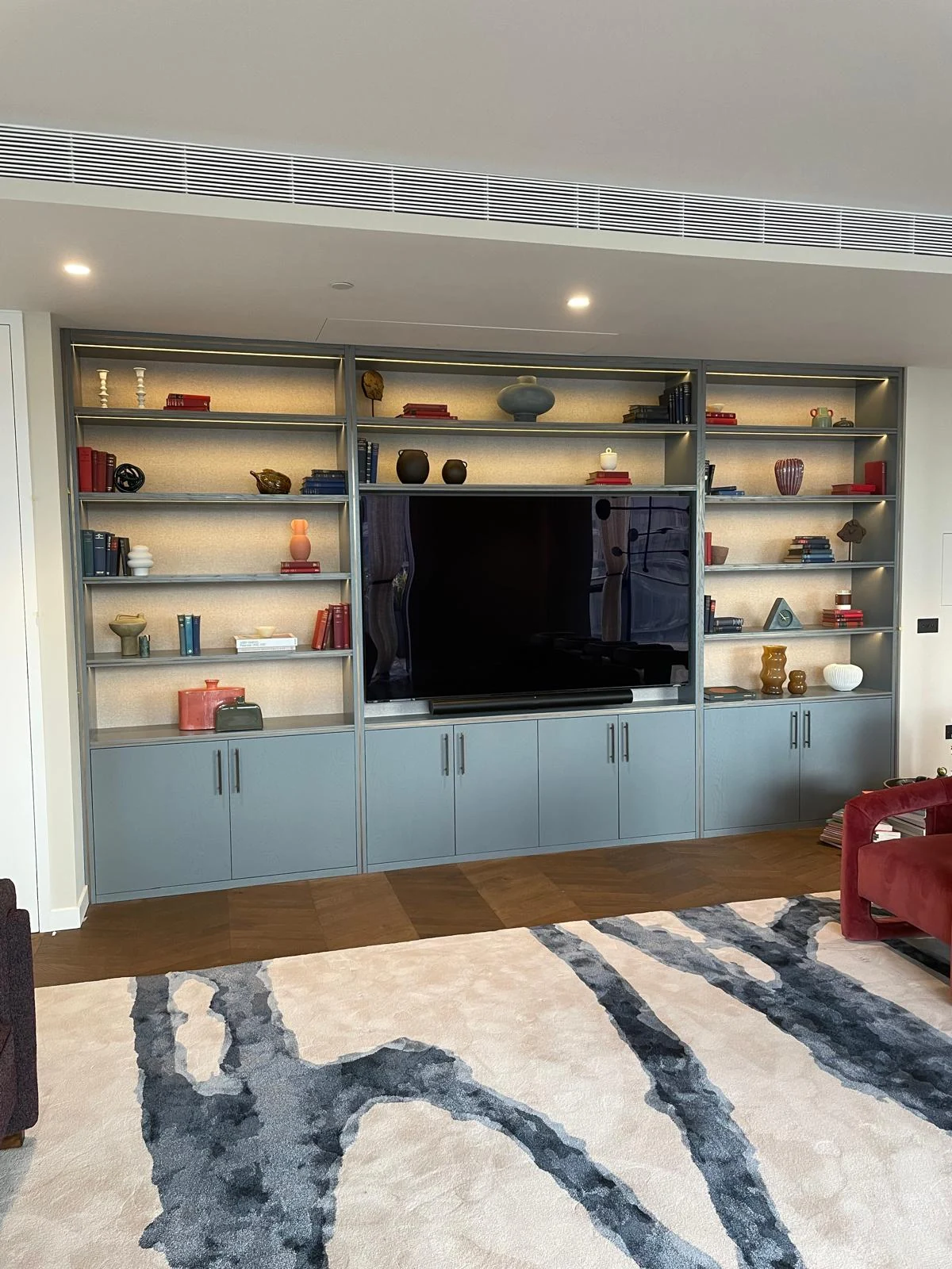 Front view of the blue-grey media wall and warm-lit display shelves.