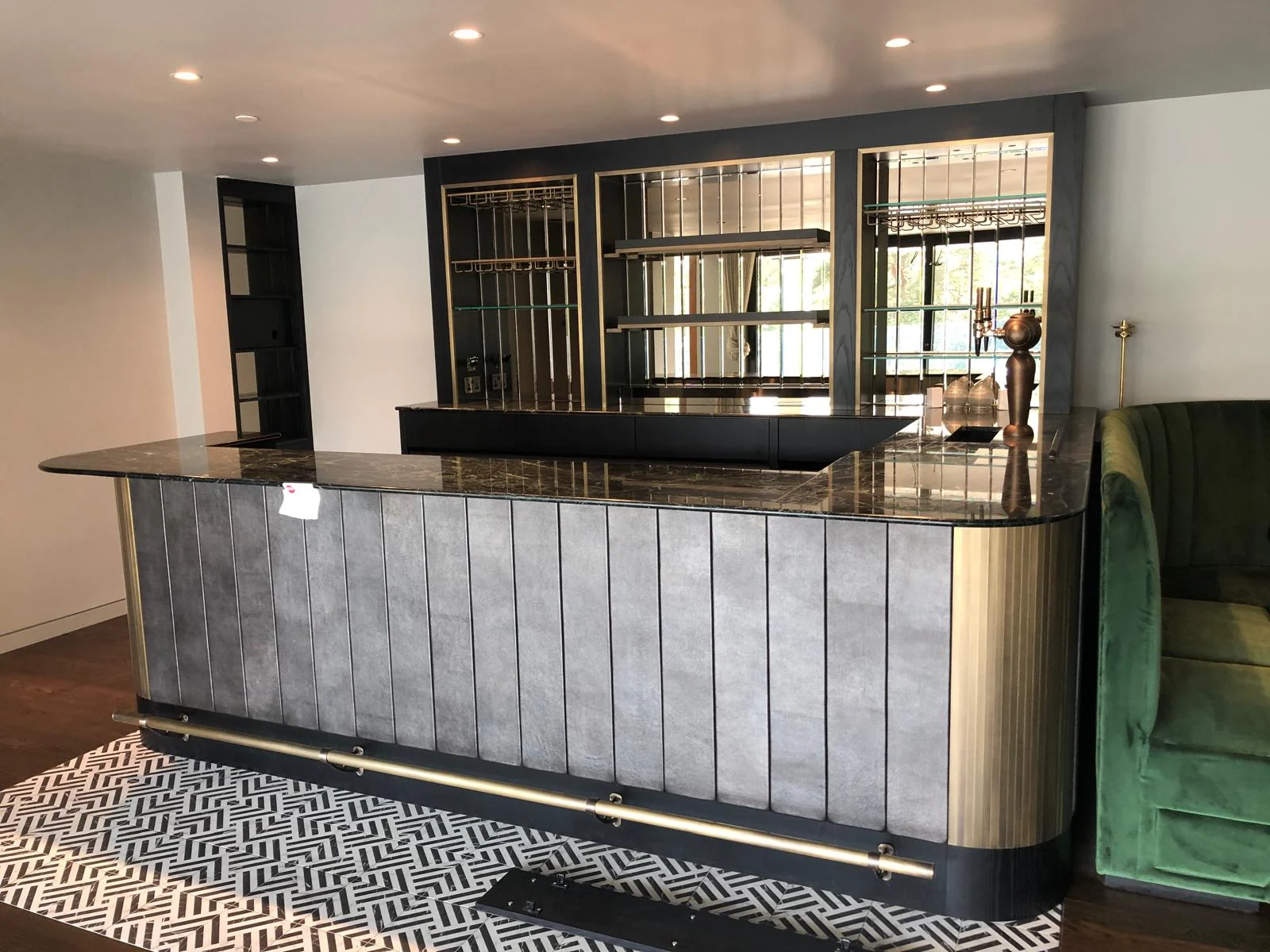 Curved decorative bar front with dark worktop and mirrored back-bar storage.
