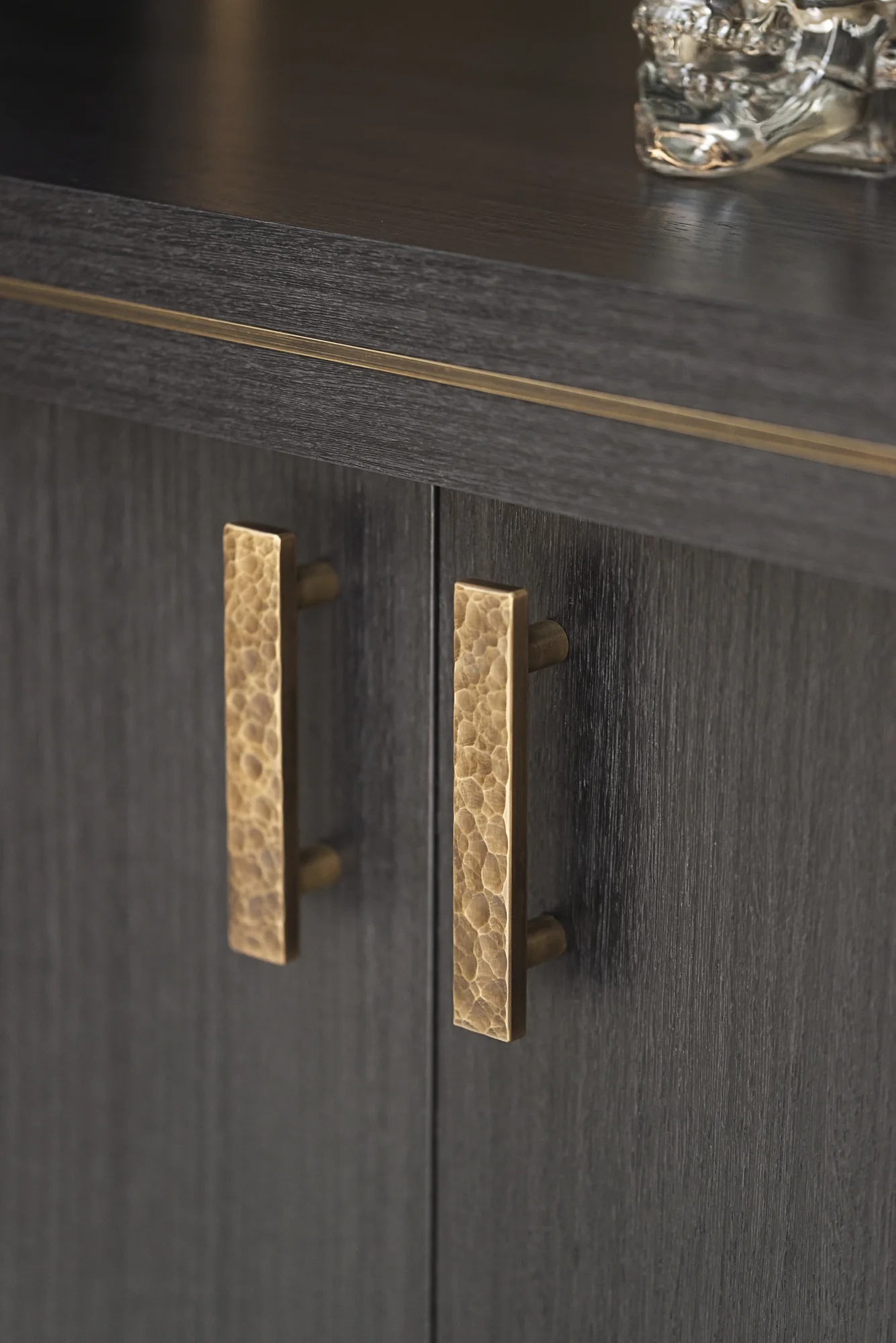 Textured metallic handles on dark dining cabinet doors