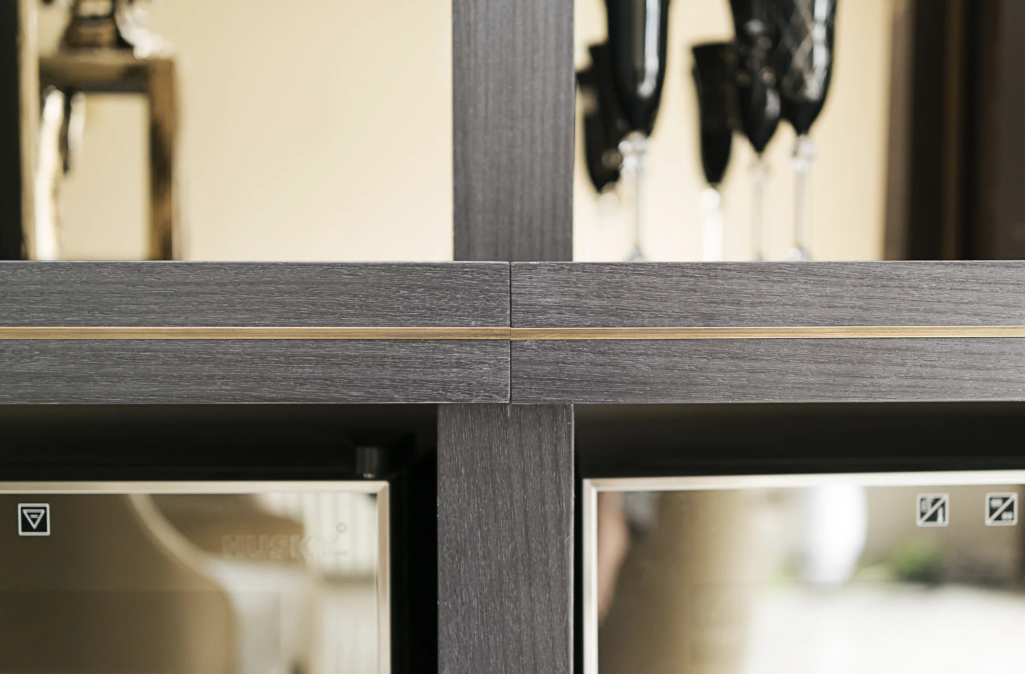 Fine metallic trim crossing the cabinet above glazed drinks storage