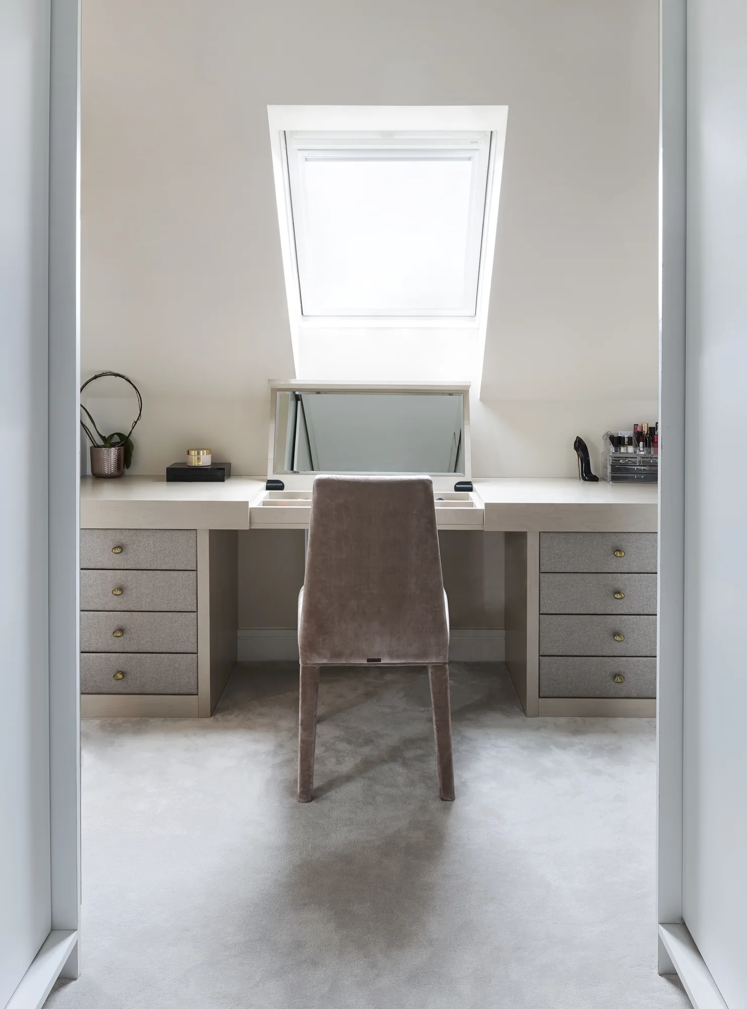Full dressing table with drawer banks and a raised mirror beneath a rooflight