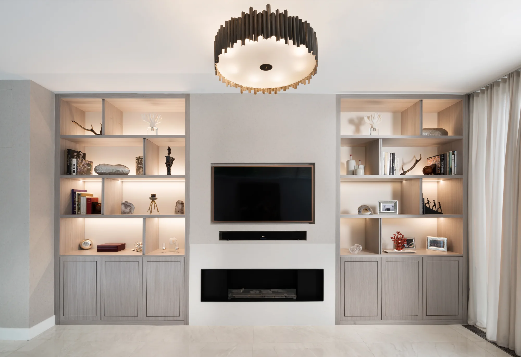 The complete media wall with twin pale wood-grain alcove units, illuminated shelves and three panelled cupboard doors on each side