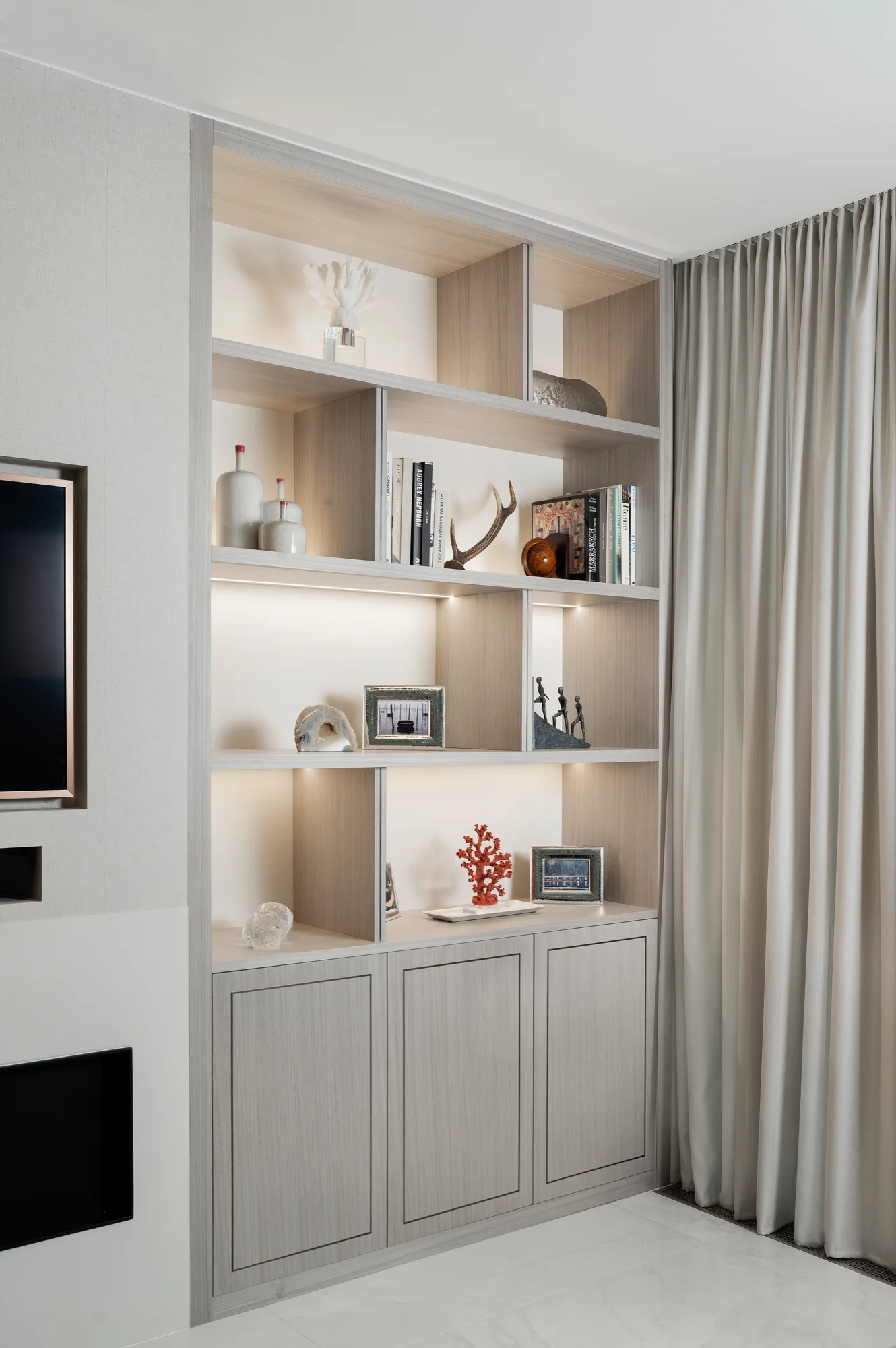 Right-hand pale wood-grain alcove unit with lit display compartments and three framed cupboard doors