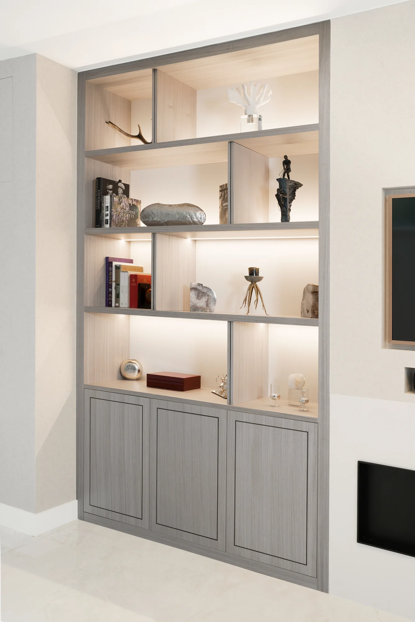 Left-hand pale wood-grain alcove unit with asymmetric open shelves above three framed cupboard doors