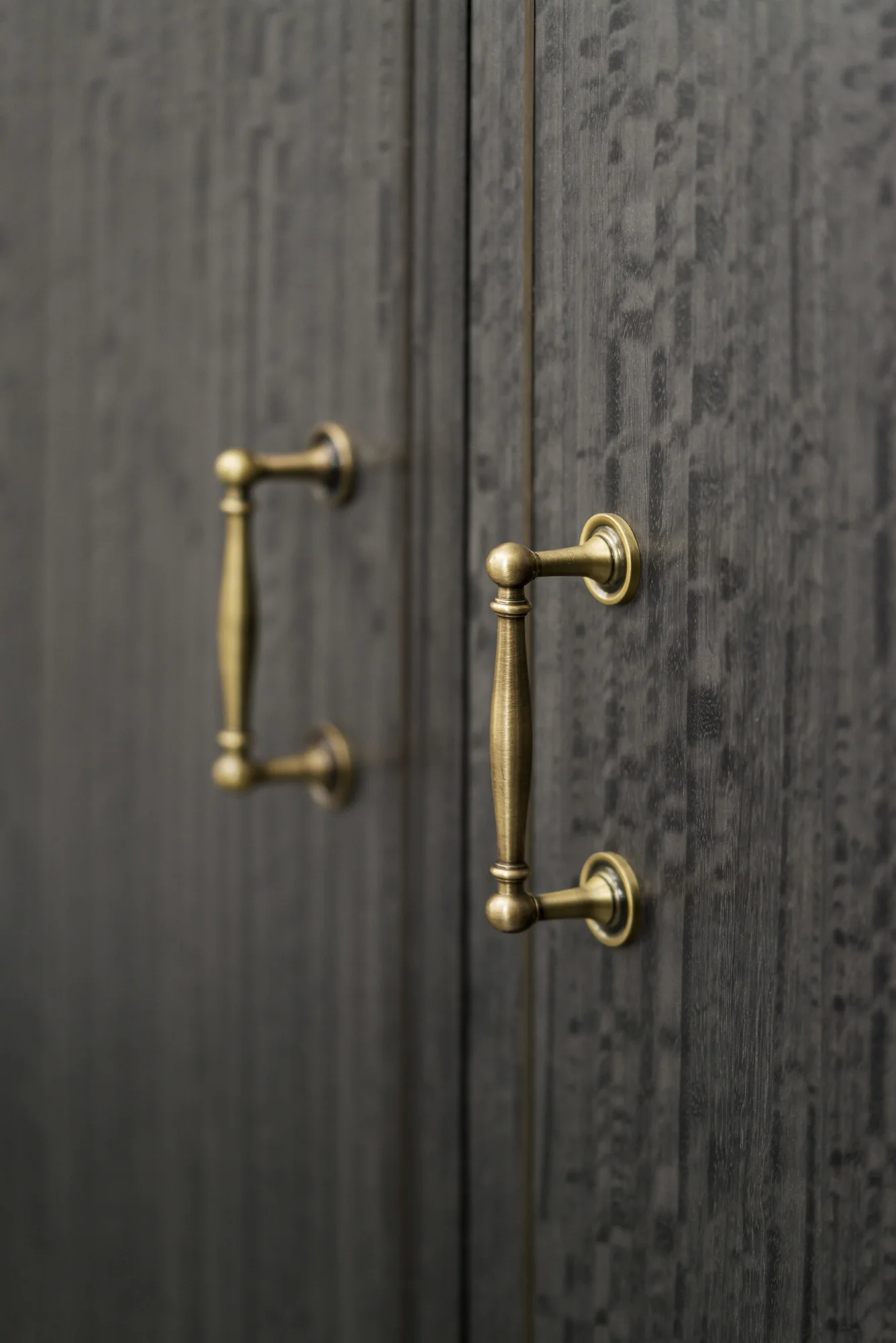 Metallic handles against the dark textured bathroom cabinet fronts