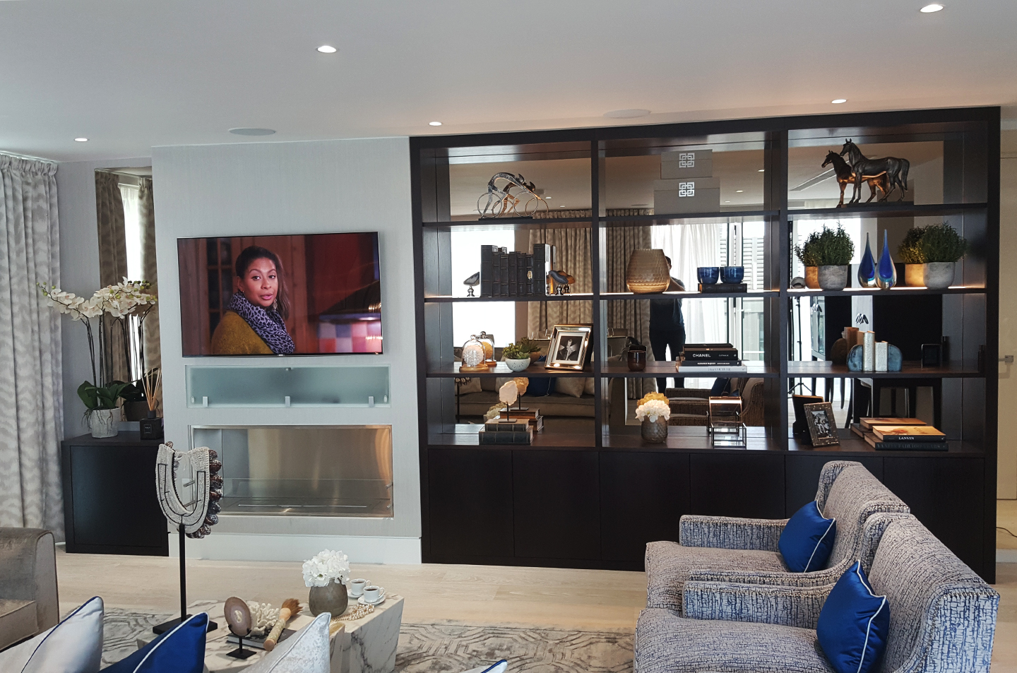 Dark fitted bookcase with illuminated display shelves and lower cupboards in