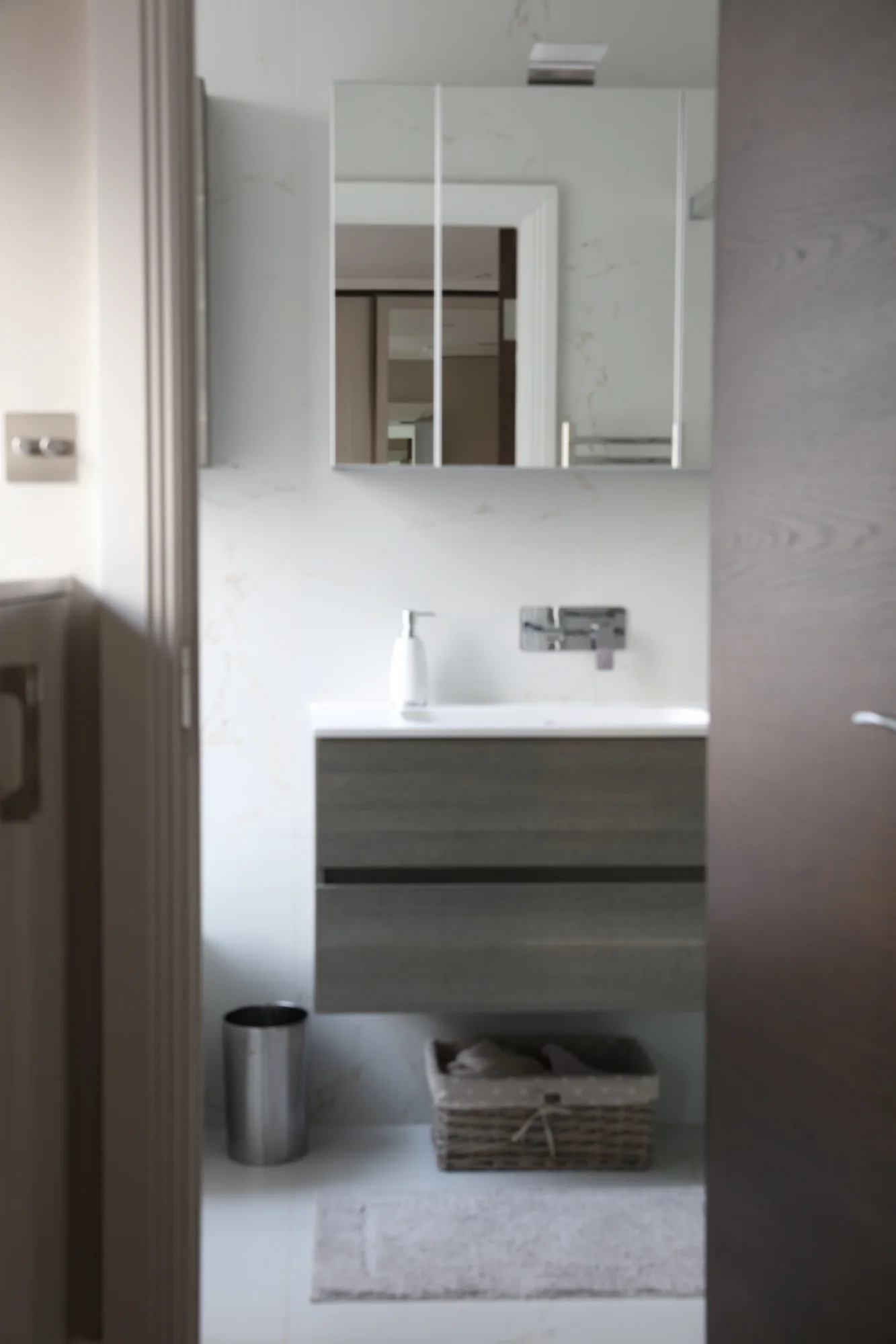 Front view of the wall-mounted vanity beneath mirrored storage