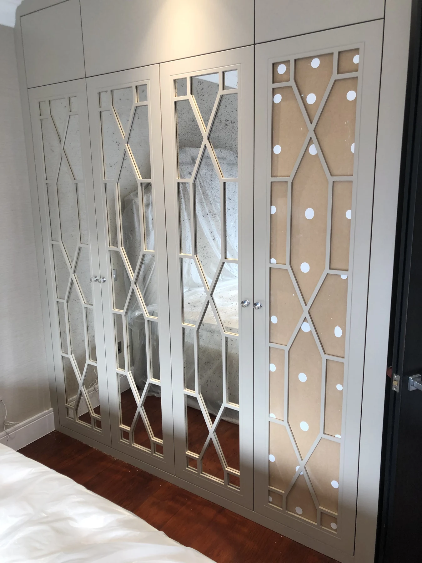 Wider view of the fitted mirrored wardrobe and its decorative door pattern.