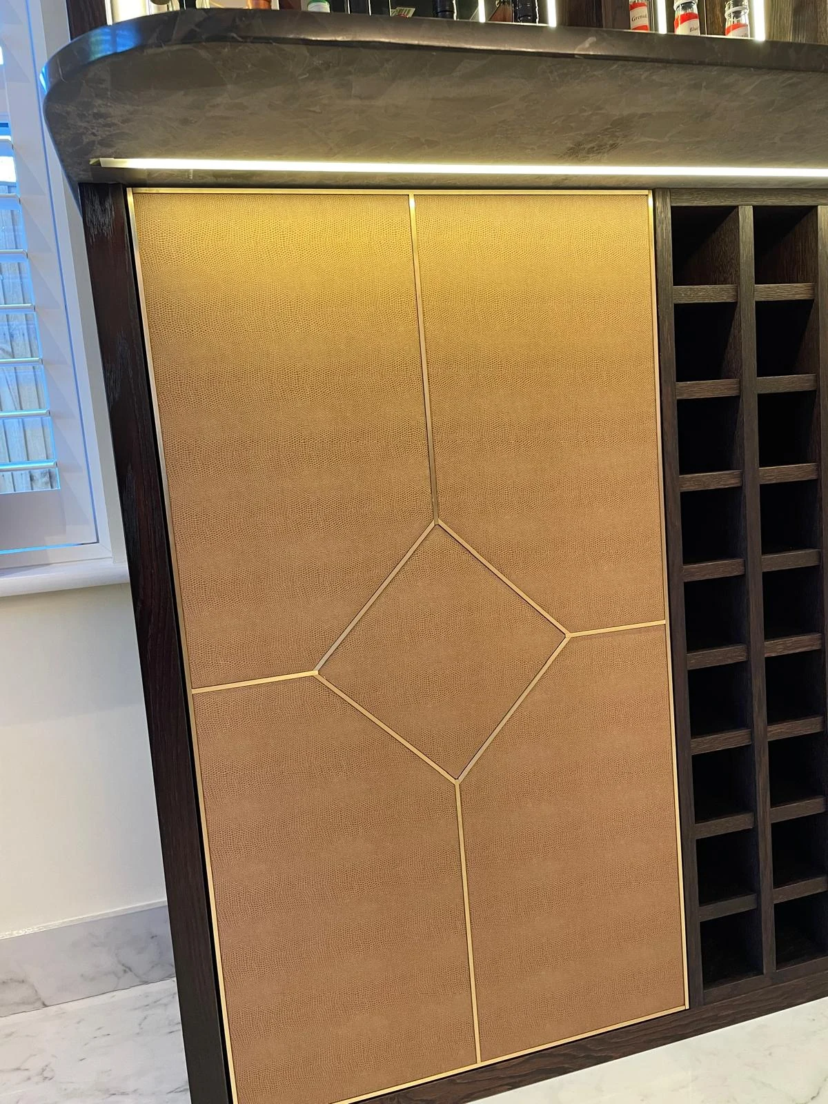 Close view of the geometric line pattern on a gold-tone cabinet door.