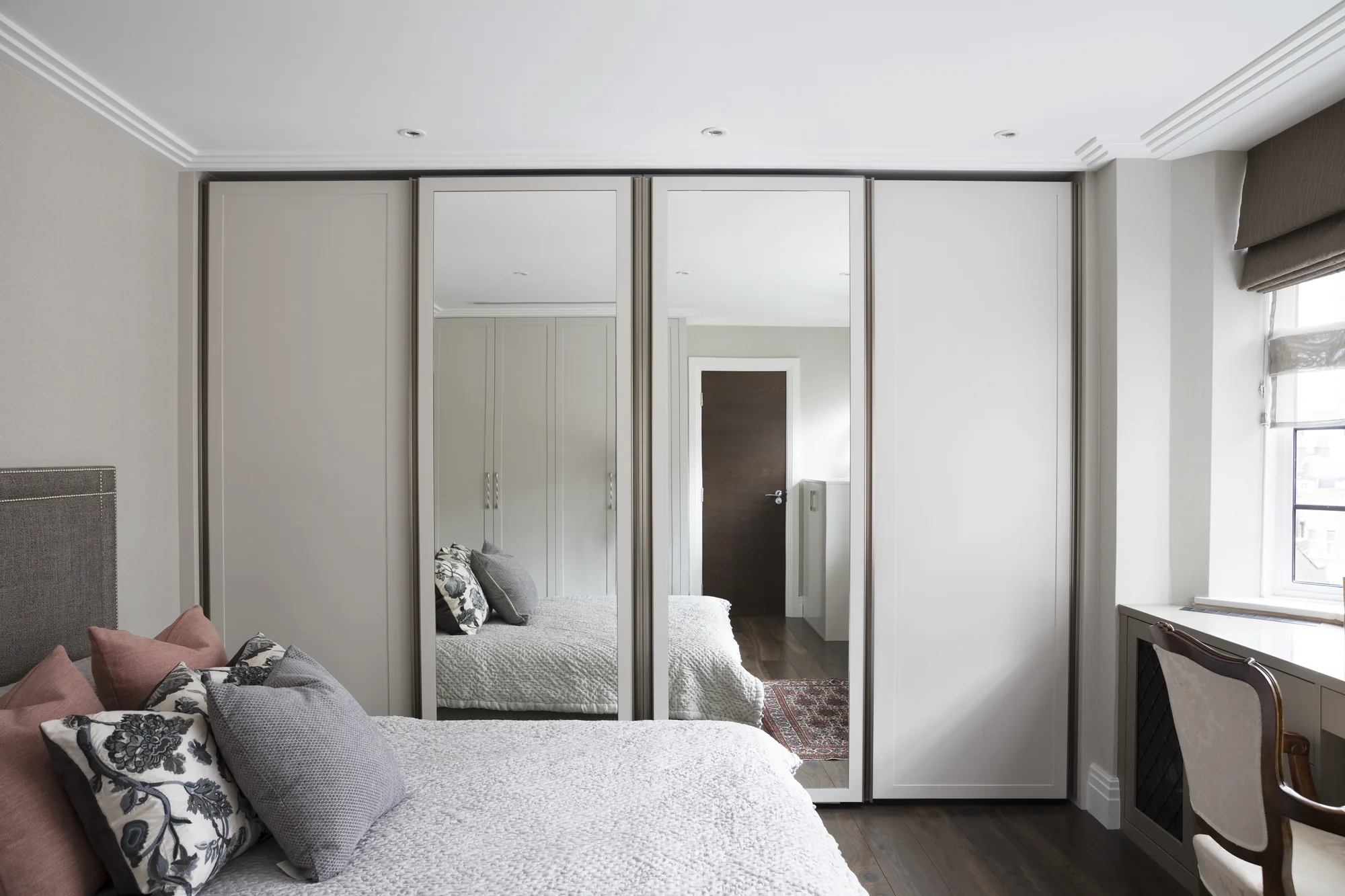 Full front view of fitted wardrobes with mirrored centre doors and pale outer panels
