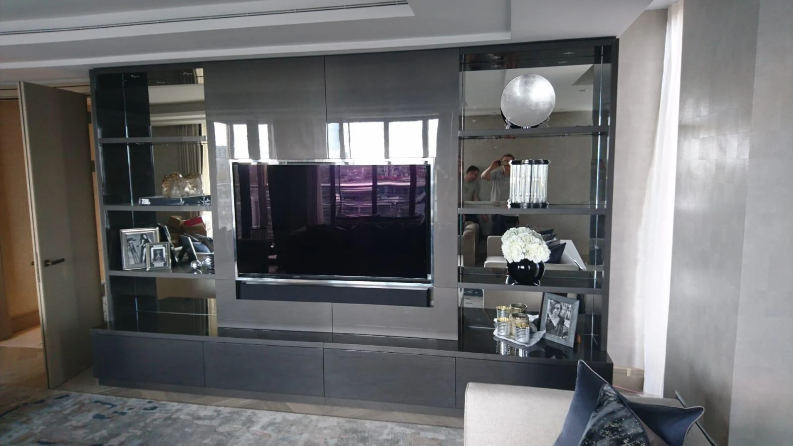 Grey media wall with television, mirrored shelving and continuous low cabinetry.