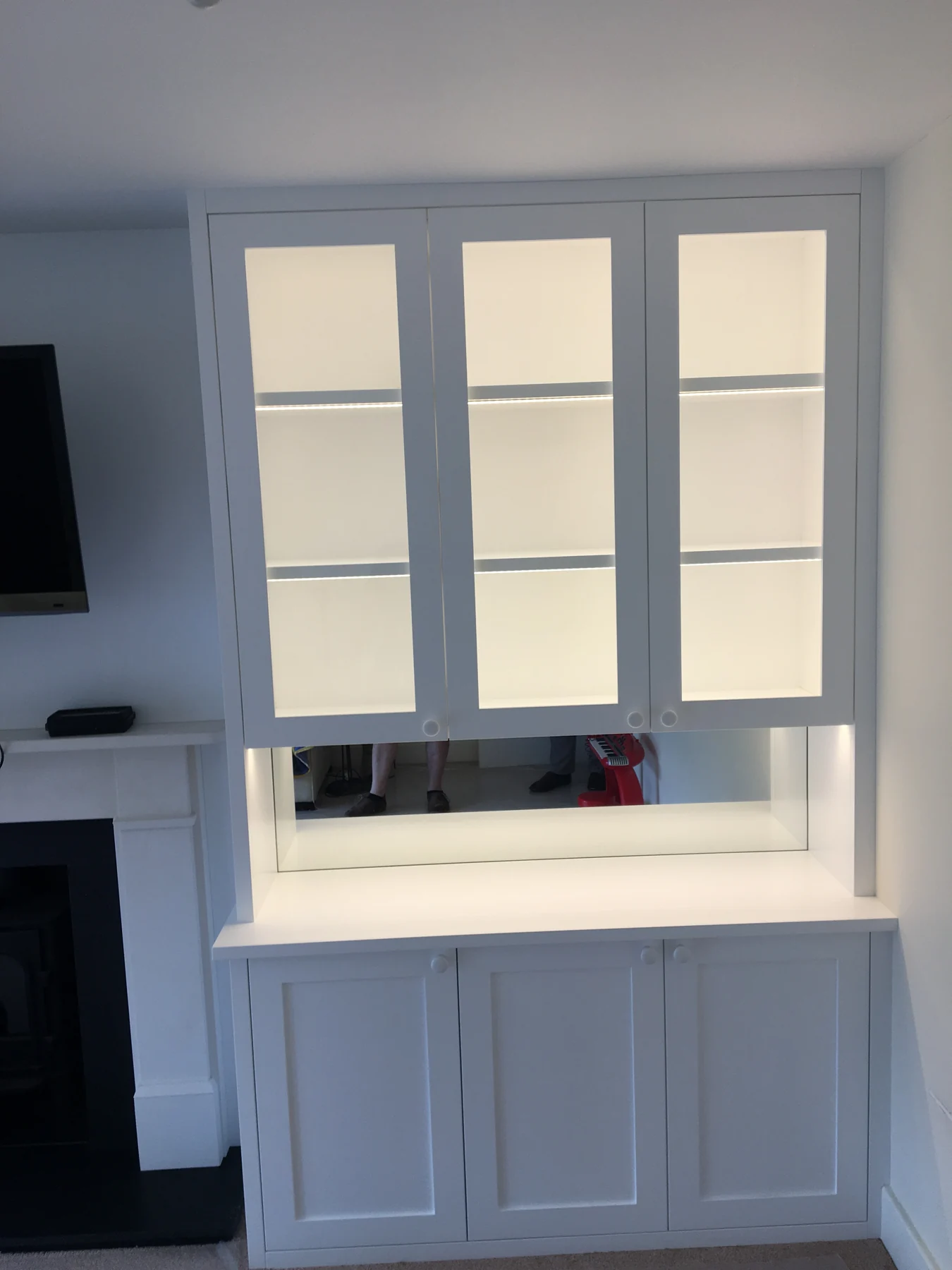 Pale display cabinet with glazed upper doors, mirrored recess and lower cupboards.