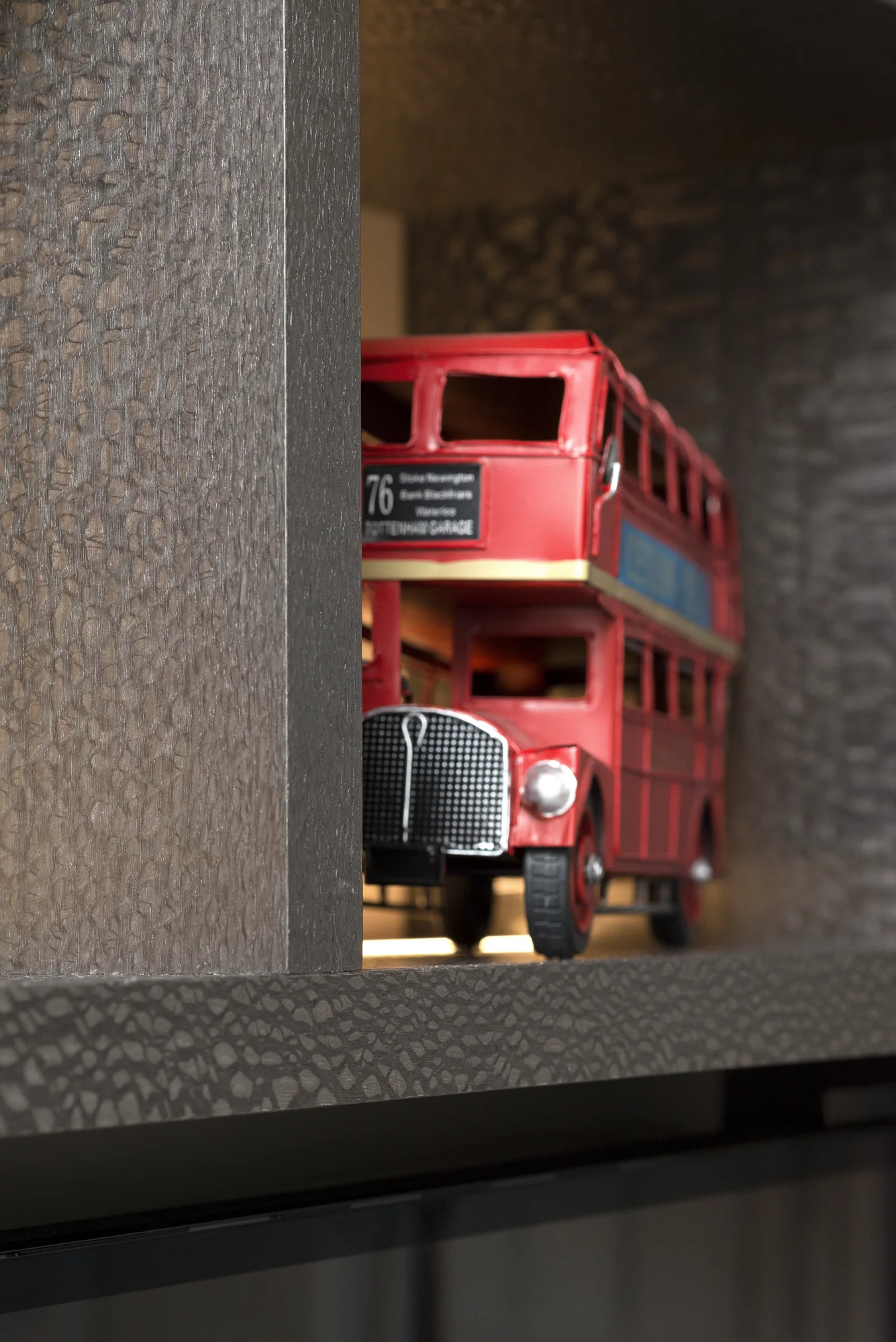 Close detail of the dark textured cabinet edge beside a display shelf