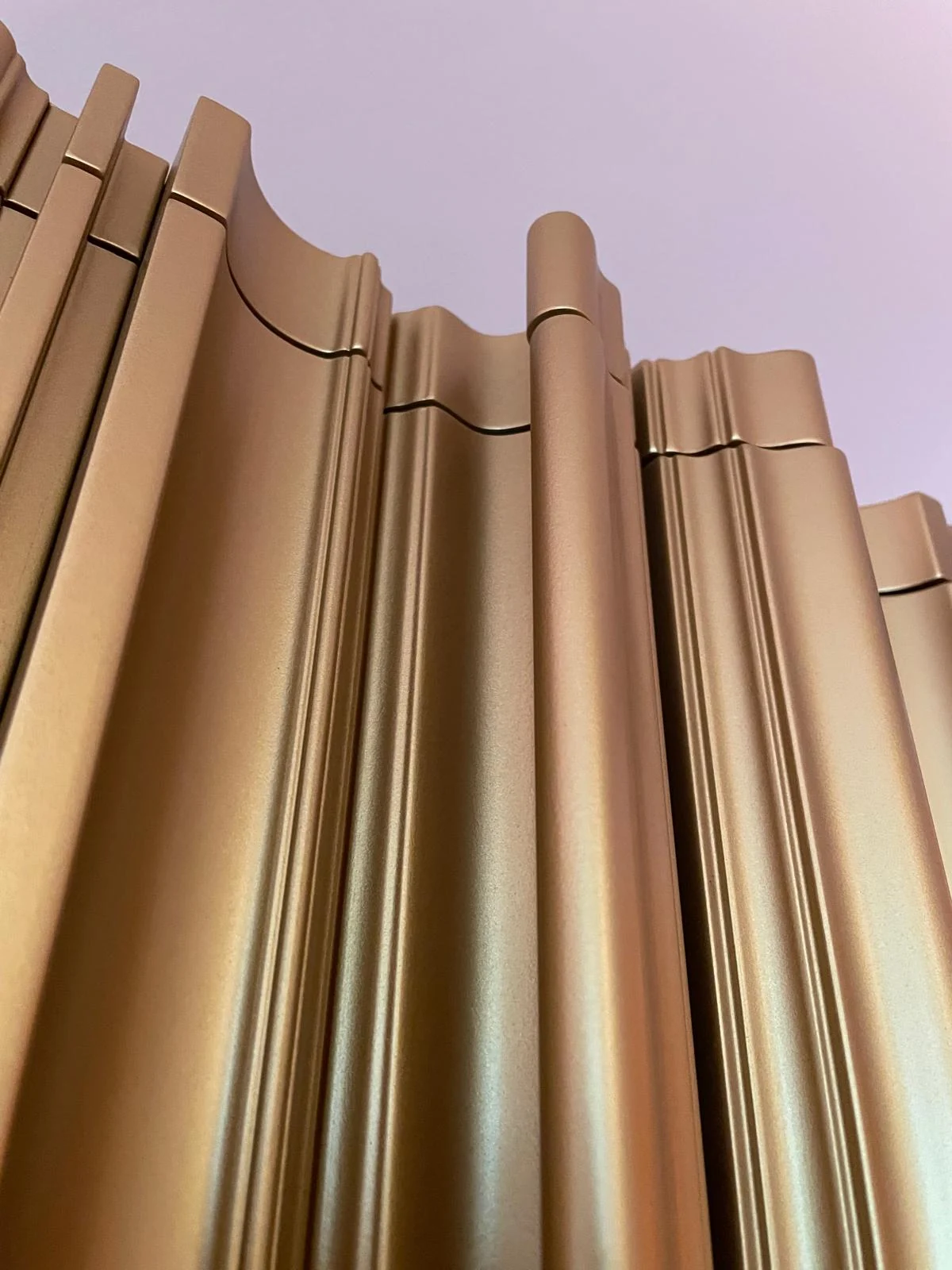 Close detail of the shaped tops and profiles of the gold-tone cabinet flutes.