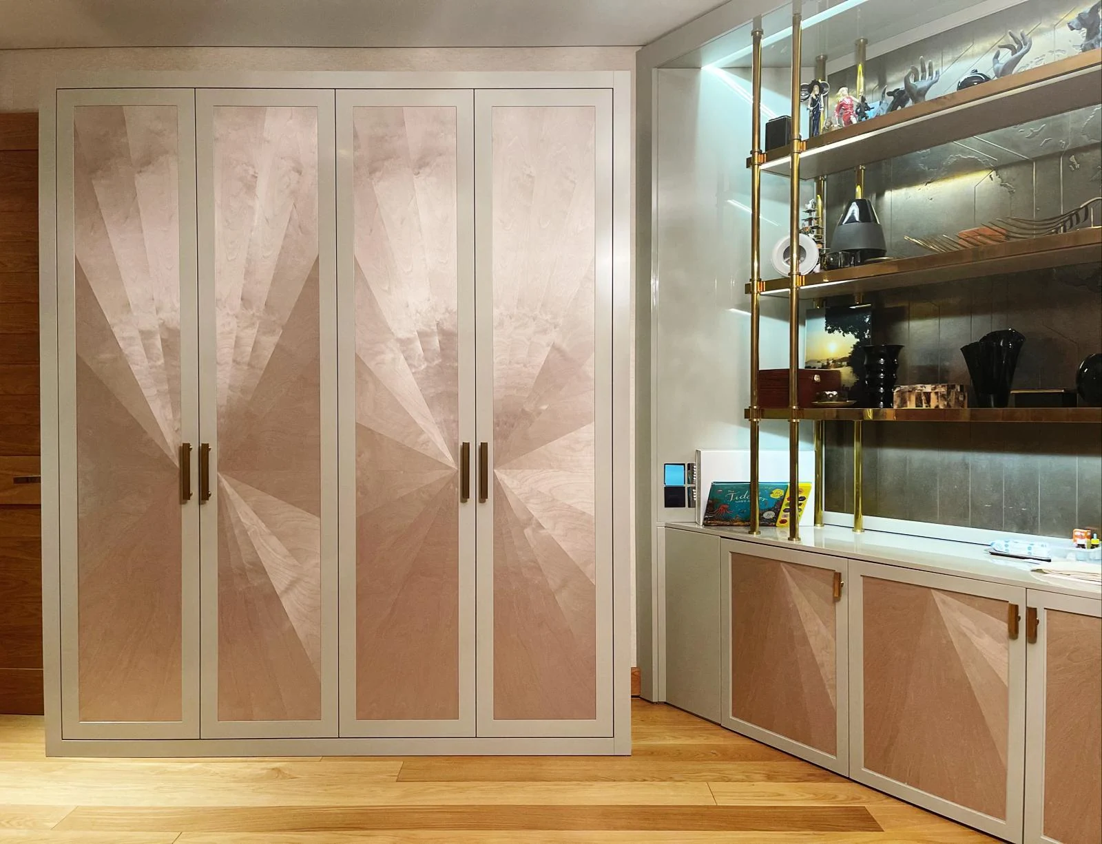 Sunburst-panel wardrobe beside a lit display cabinet and matching lower doors.