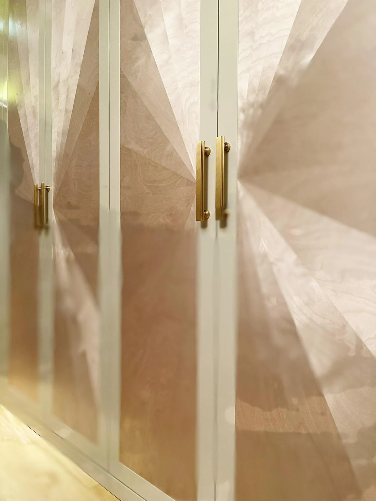 Oblique detail of radial door patterns and brass-tone handles.
