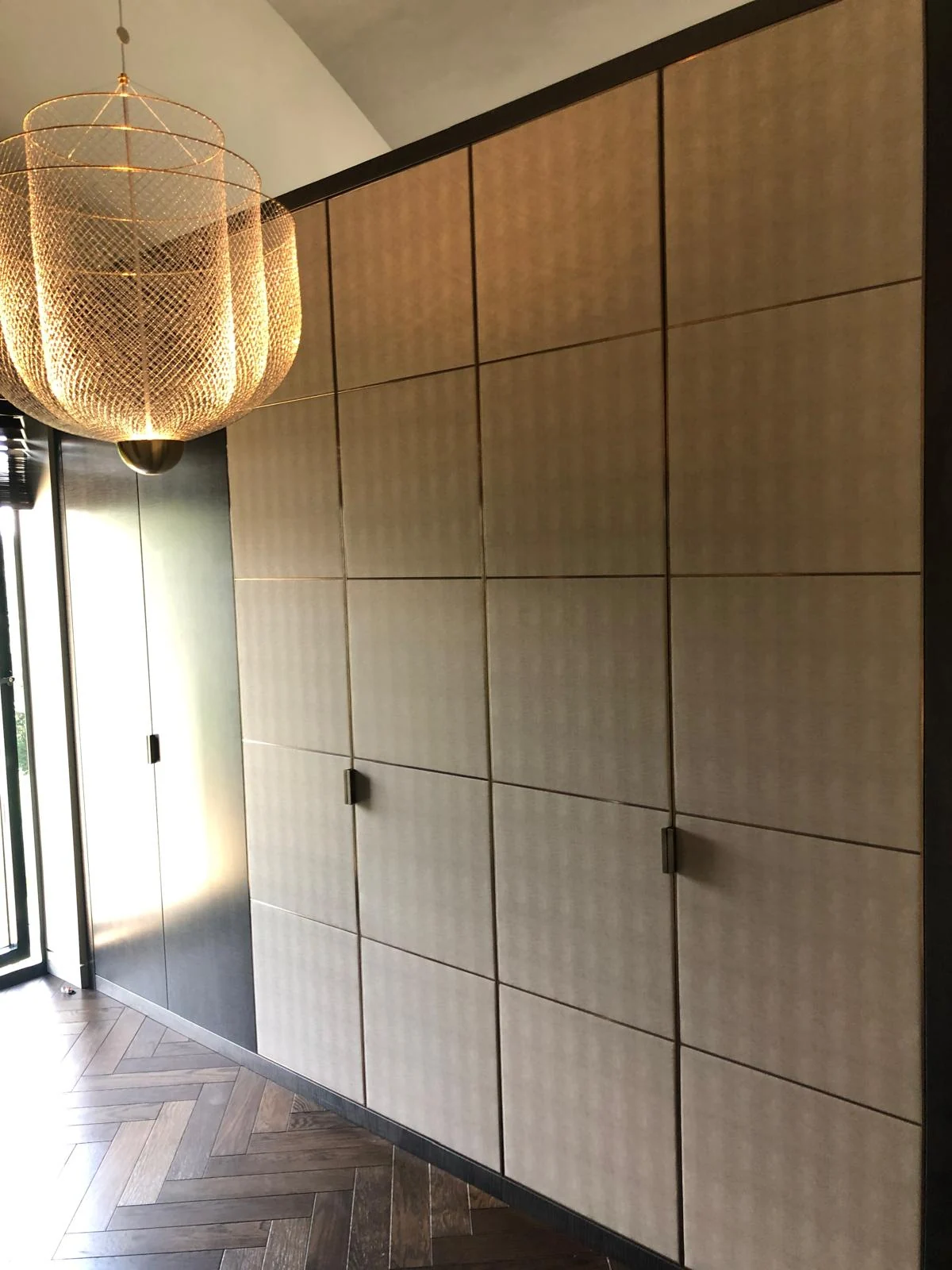 Full-height wardrobe with a grid of textured panels and dark framing.