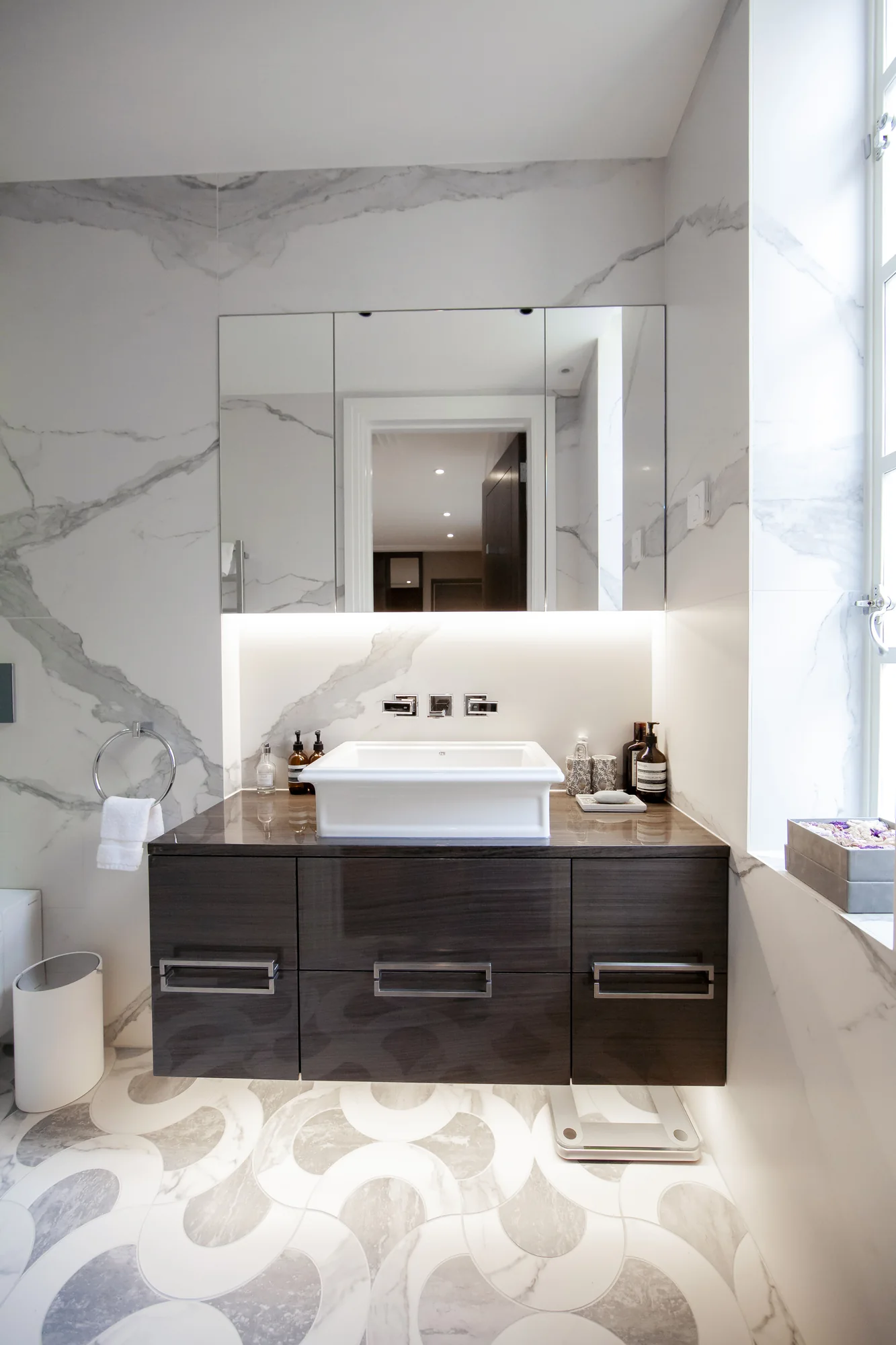 Wall-mounted dark vanity with rectangular handles beneath a white rectangular basin