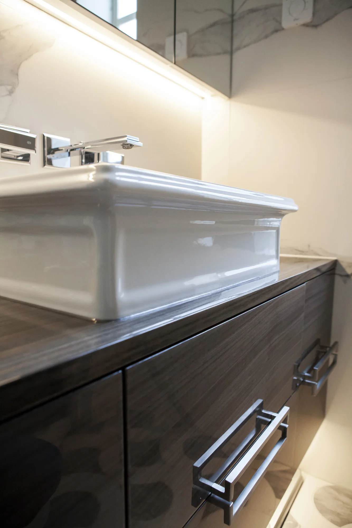 Side detail of the raised basin, dark vanity front and rectangular metallic handles