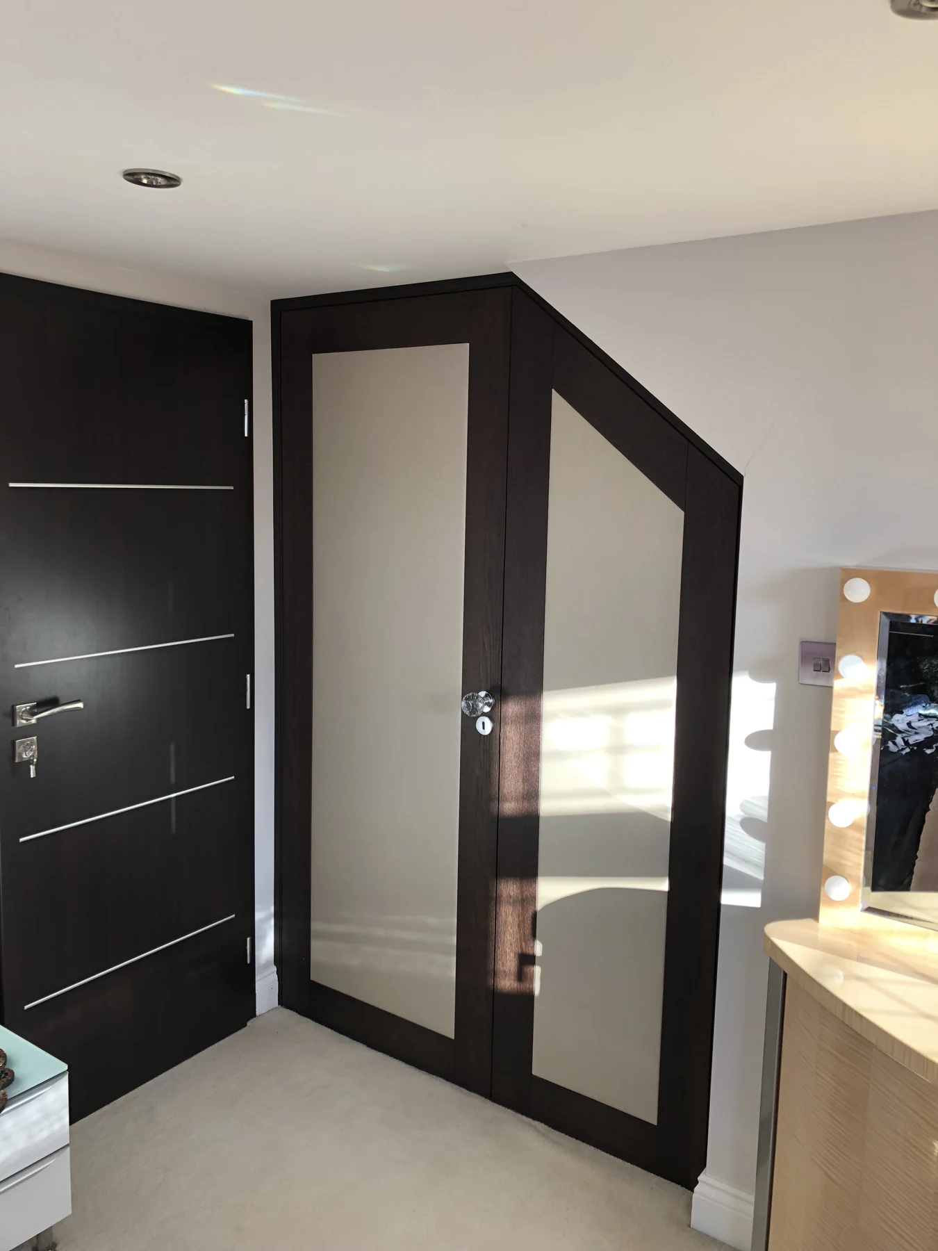 Two-tone fitted wardrobe shaped to fit beneath a sloping ceiling.