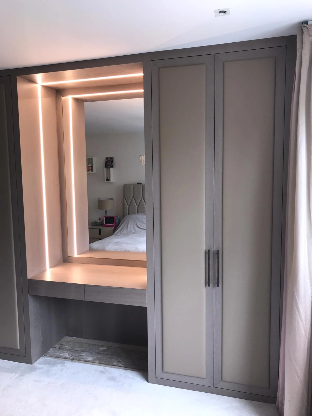 Angled view of the grey wardrobe and illuminated dressing recess.