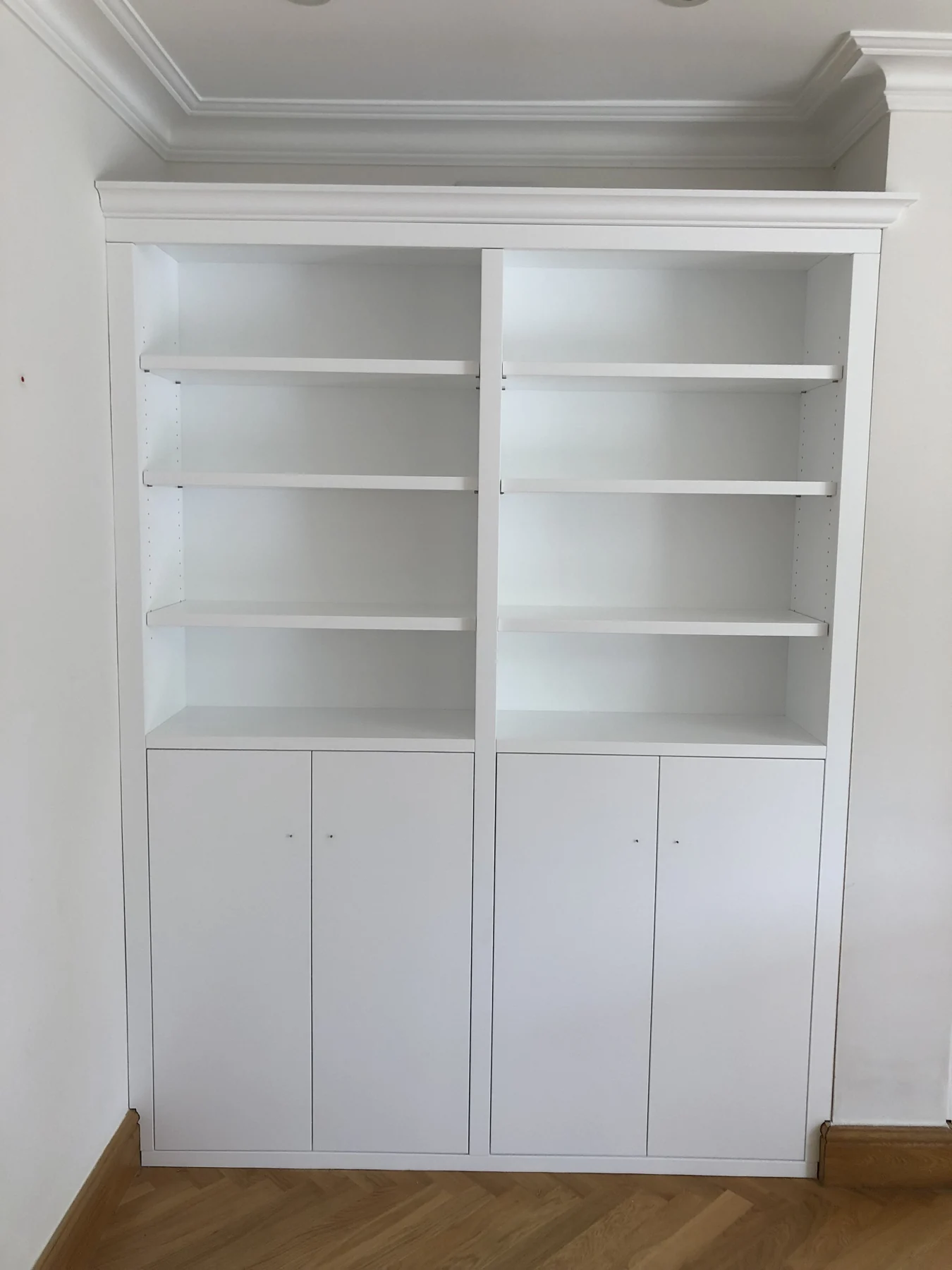 White alcove bookcase with a cornice, open shelving and low cupboards.
