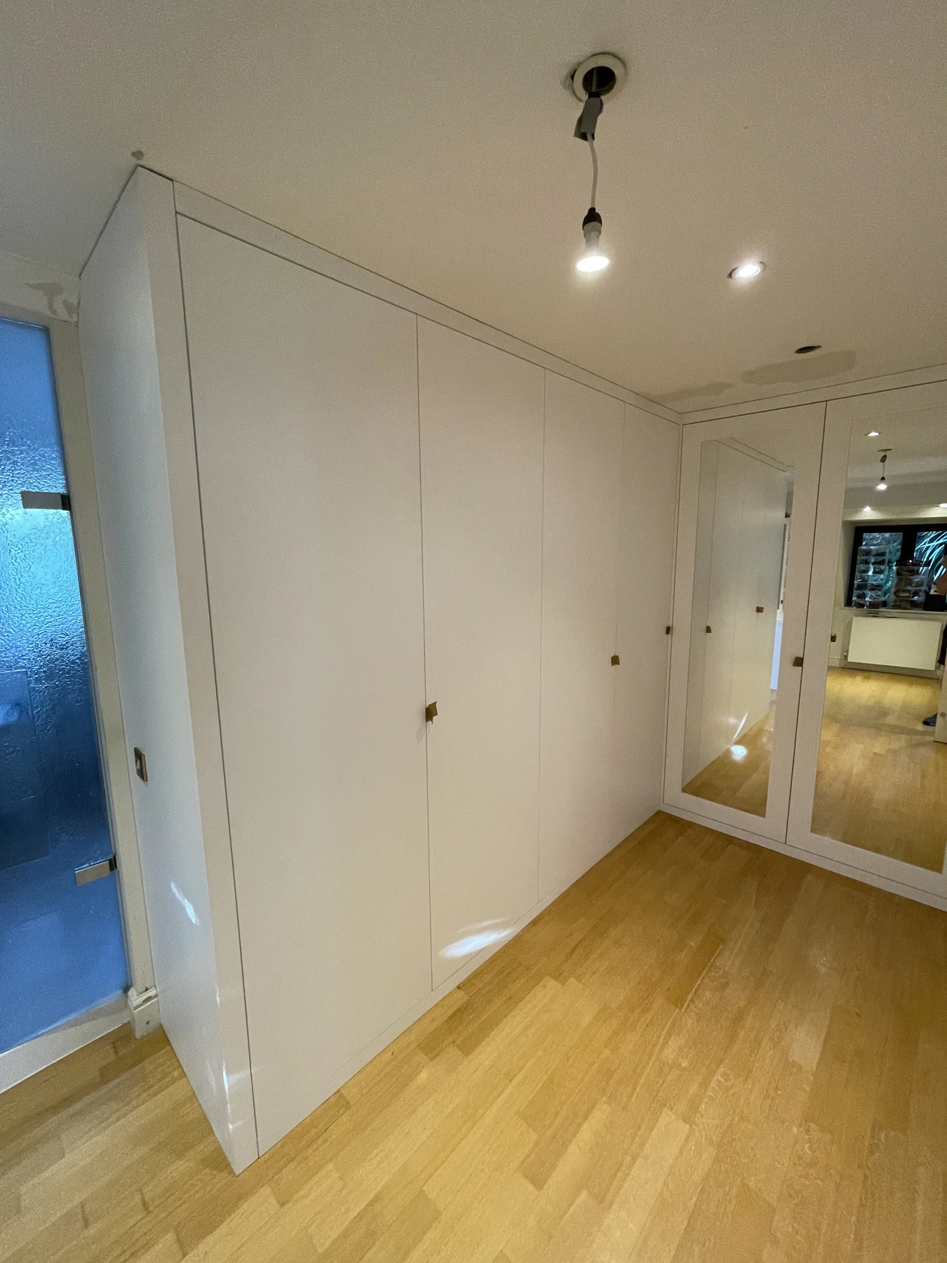 Long run of white fitted wardrobes beneath the ceiling.