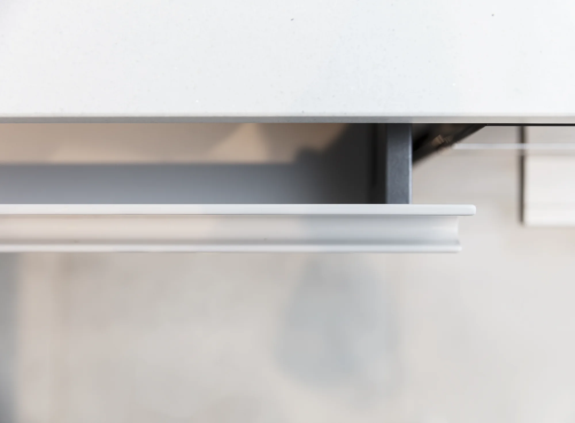 Close-up of the recessed handle profile on a white kitchen drawer