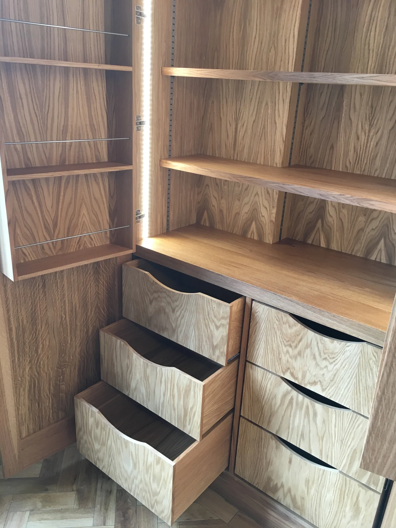 Close view of open internal drawers and illuminated wood-grain shelving.